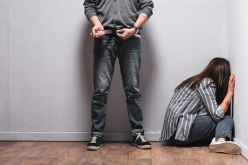  taking off waist belt near woman with bruise on hand sitting on floor beside walls