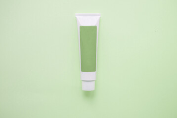 one green tube cream of personal care cosmetics on a green background, place for your name 