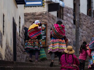 Indigenous quechua women in traditional colorful handwoven textile clothing dress costume walking...