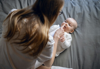 Happy woman looks at her baby and smiles. Beautiful baby smiles at mother. Mother with her own baby.