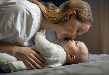 Happy woman looks at her baby and smiles. Beautiful baby smiles at mother. Mother with her own baby.