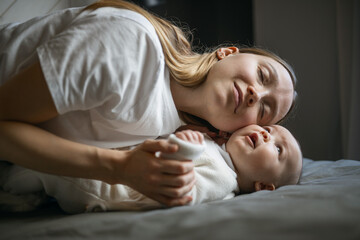 Beautiful mother with her baby. Young beautiful woman looks at her little daughter. Baby girl laughing in her mother's arms.