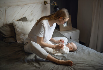 Mom with her baby lies and looks at the camera from the top. Beautiful young woman with her baby. Mother and daughter. Happy family.