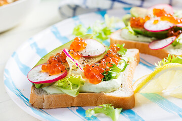 Sandwiches with salmon red caviar with sliced avocado and radish. Sandwich for lunch. Premium food