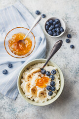 Breakfast with Milk rice porridge with banans, blueberry and orange jam, creamy rice pudding or french riz au lait in a bowl. Top view