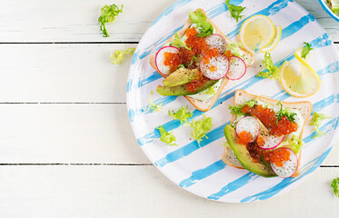 Sandwiches with salmon red caviar with sliced avocado and radish. Sandwich for lunch. Premium food. Overhead, top view, flat lay