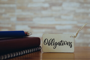 Selective focus of notebooks, pen and wooden board written with text OBLIGATIONS. Business concept. 
