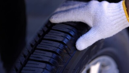 A car maintenance worker is checking the quality of the tires that are worn out, should they be replaced or not He takes care of the car for the customer.

