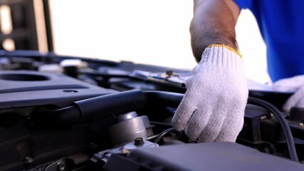 A young Asian auto mechanic opens the bonnet. To check for engine damage And perform professional maintenance. He wearing blue uniform.
