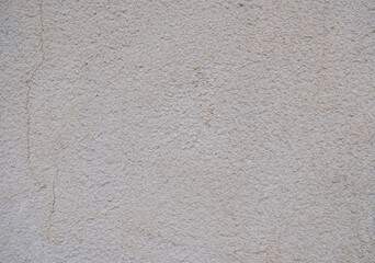 Textured background of an old wall made of beige plaster. Smooth surface. Cracks. Copy space.