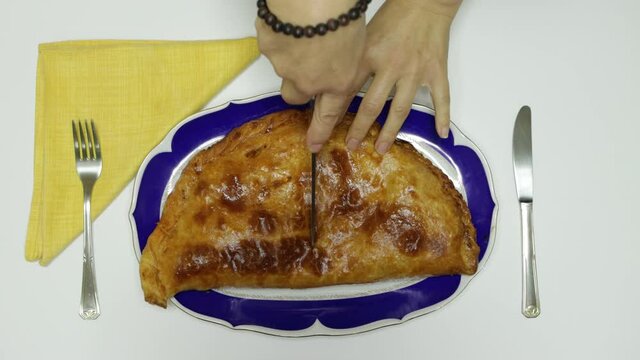 Cutting a typical Galician homemade tuna and pepper empanada in half.