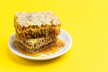 Honey in combs in a plate on a yellow background