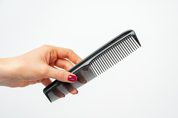Female hand holding hair comb against white background