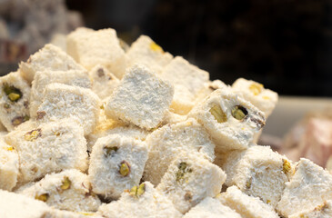 Turkish Delight close-up. White pieces of the oriental sweets with nuts and pistachios macro.