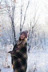 Fototapeta na wymiar beautiful young woman in plaid blanket smiles and laughs on a winter walk