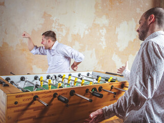 A man celebrates a victory in table football. Evening activities and relaxation.