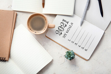 Notebook with to-do list for 2021, cup of coffee and stationery on white background