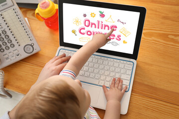 Young mother with baby using laptop for online learning at home