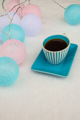 Black coffee in a blue cup around garland of balloons
