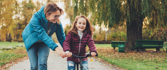 Charming caucasian mother teaching her small girl to dive the bike in the park © Strelciuc