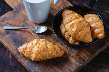 Breakfast bread, croissants and fresh milk on the wooden table.
