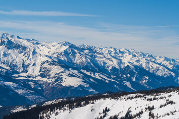 Snowy mountain peaks in the Zell am See area of Austria. In the background is a blue sky with dramatic clouds.