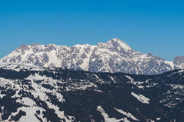 Snowy mountain peaks in the Zell am See area of Austria. In the background is a blue sky with dramatic clouds.