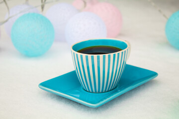 Black coffee in a blue cup around garland of balloons