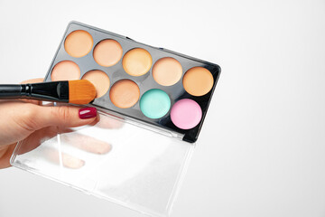 Female hand holding make up palette against white background