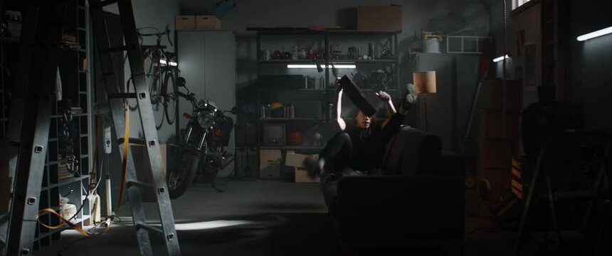WIDE Caucasian teenager boy entering his home garage hideout, grabbing acoustic guitar. Shot with 2x anamorphic lens