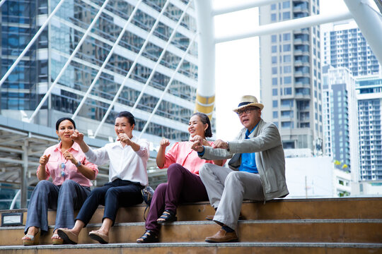 Travel And Tourism Concept. Group Of Happy Asian Elderly Traveller Is Sitting On The Stairs.