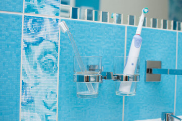 Electric toothbrush vs. manual toothbrush in bathroom. Oral care and prevention concept