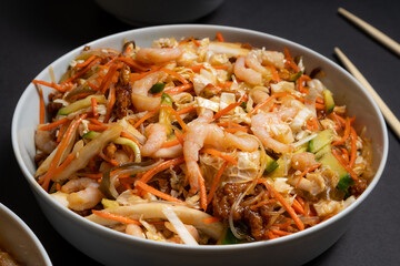Vibrant plate of shrimp salad. Traditional prawn salad with vegetables. Colorful bowl with seafood on black background.