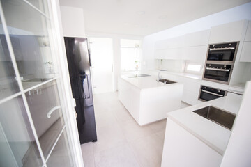 White organised kitchen with modern elements in an apartment . High quality photo