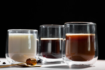 Glass cups of coffee and milk on white table