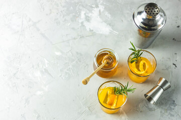  rosemary simple syrup or homemade whiskey sour cocktail drink with orange and rosemary. Decorate orange peel. Light concrete surface