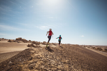 Two women trail runners cross country running in the desert