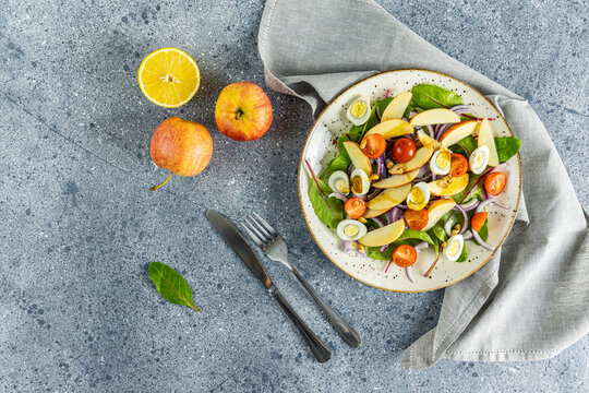 Healthy Delicious Tasty Salad With  Lettuce, Tomatoes, Eggs, Apples, Lemon Juice And Nuts In Light Plate On Grey Table Surface