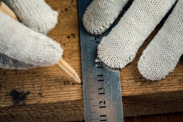 The concept of making wood products and furniture. Carpenter in the workshop marks out details close-up.