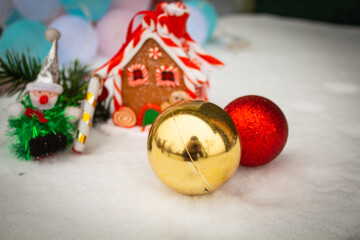 Christmas balls in the snow next to a gingerbread house 