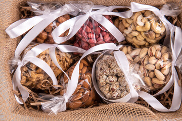 set of nuts in a gift transparent packaging tied with a white ribbon on a burlap on a white background