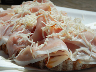 close up of a ham sandwich with horseradish on a white plate