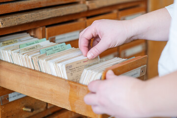 Hands fingering cards in a vintage library card file