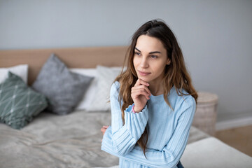 Relaxed smiling woman sitting on sofa at home.