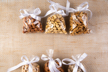 set of nuts in a gift transparent packaging tied with a white ribbon on a sackcloth on a white background with free space for an inscription