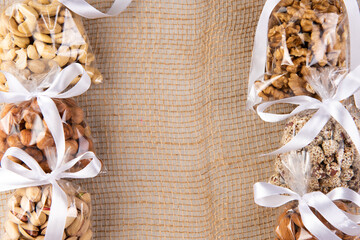 set of nuts in a gift transparent packaging tied with a white ribbon on a sackcloth on a white background with free space for an inscription