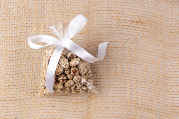 peanuts in kujut in a gift transparent package tied with a white ribbon on a burlap on a white background