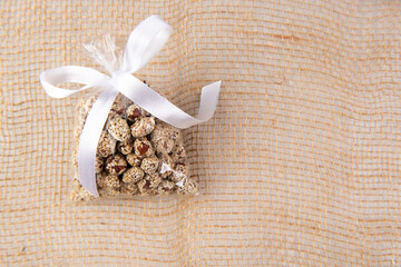 peanuts in kujut in a gift transparent package tied with a white ribbon on a burlap on a white background