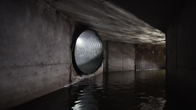 Concrete sewer or drainage collector filled with water, in which a round plastic pipe is connected.	
