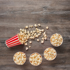 Top view of five paper cups with red stripes and popcorn